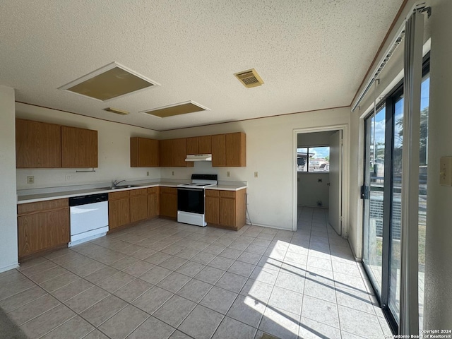 kitchen featuring visible vents, under cabinet range hood, a sink, white appliances, and light countertops