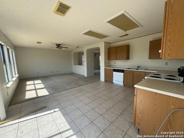 kitchen featuring white appliances, visible vents, a sink, open floor plan, and brown cabinets