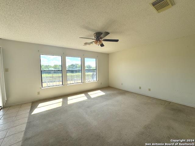 unfurnished room featuring visible vents, a textured ceiling, and a ceiling fan