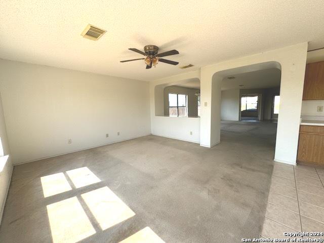 unfurnished room featuring visible vents, arched walkways, a textured ceiling, and a ceiling fan