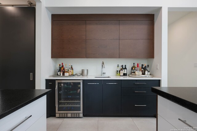 bar featuring light tile patterned floors, beverage cooler, sink, and white cabinets