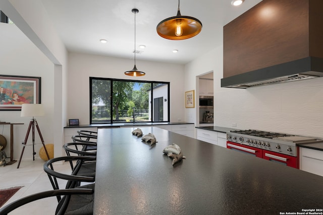 kitchen featuring high end stainless steel range, custom exhaust hood, light tile patterned floors, decorative backsplash, and hanging light fixtures