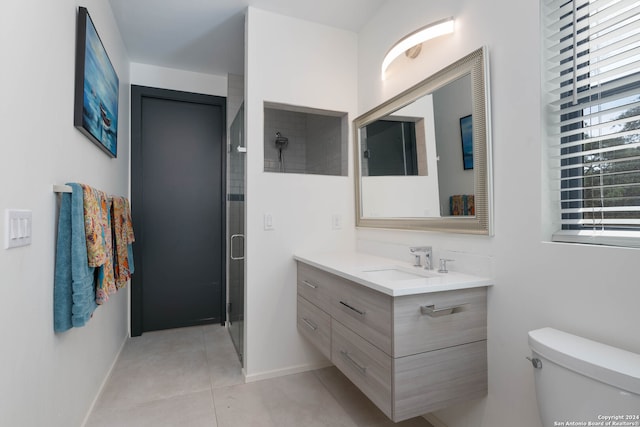 bathroom featuring tile patterned floors, vanity, toilet, and a shower with shower door