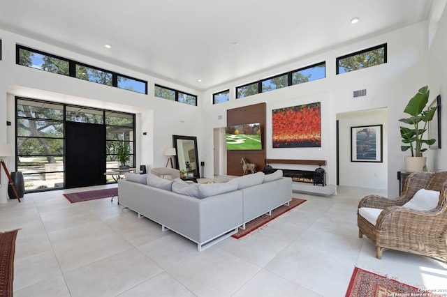 living room featuring light tile patterned flooring and a towering ceiling