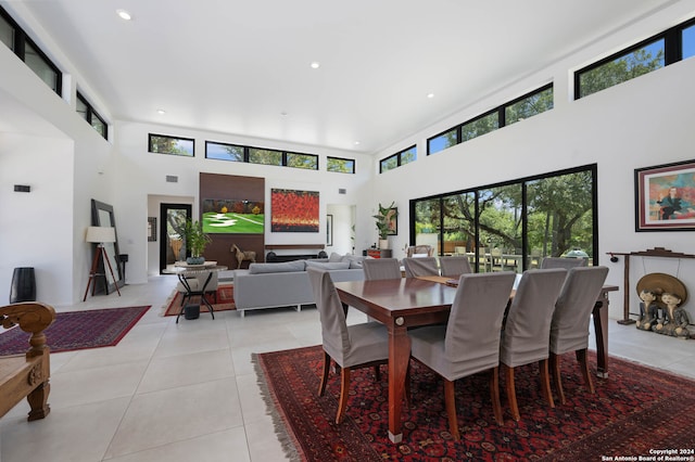 dining area with a healthy amount of sunlight, light tile patterned flooring, and a high ceiling