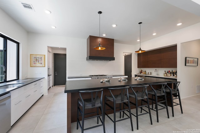 kitchen featuring tasteful backsplash, decorative light fixtures, an island with sink, sink, and stainless steel dishwasher