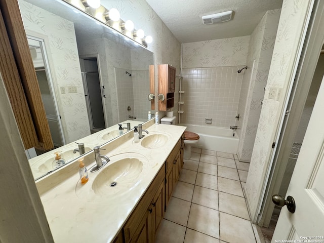 full bathroom featuring toilet, tile patterned floors, tiled shower / bath, vanity, and a textured ceiling