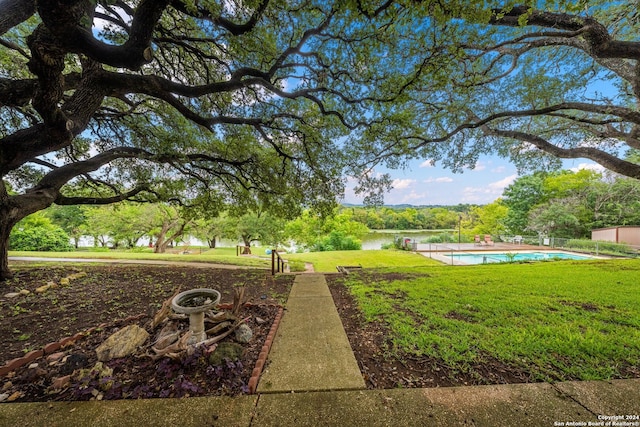 view of community featuring a lawn, a pool, and a water view