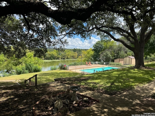 view of pool featuring a yard, a storage unit, and a water view