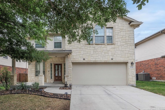 traditional home featuring central air condition unit, stone siding, driveway, and a garage