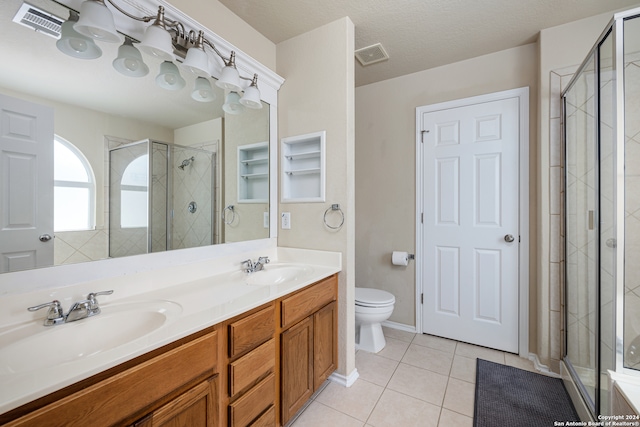 bathroom with tile patterned floors, vanity, toilet, a shower with shower door, and a textured ceiling