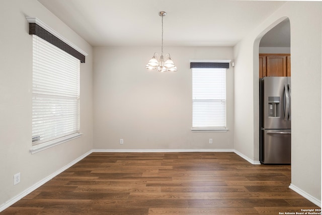 unfurnished dining area featuring plenty of natural light, dark hardwood / wood-style floors, and an inviting chandelier