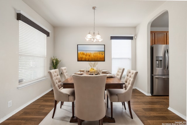 dining room featuring arched walkways, baseboards, dark wood finished floors, and an inviting chandelier