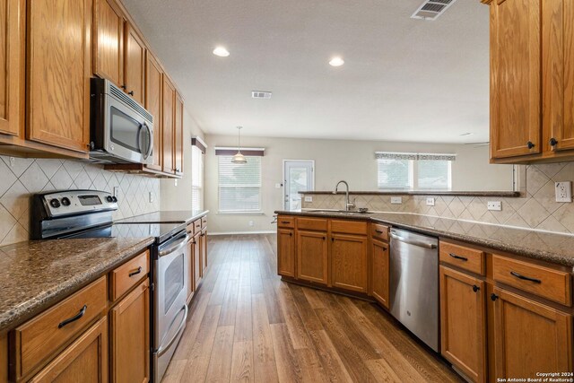 kitchen featuring plenty of natural light, backsplash, appliances with stainless steel finishes, and hardwood / wood-style flooring