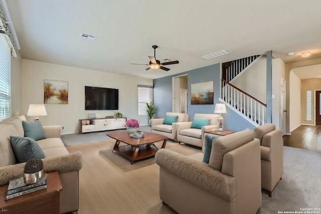 living area with ceiling fan, stairway, wood finished floors, and visible vents