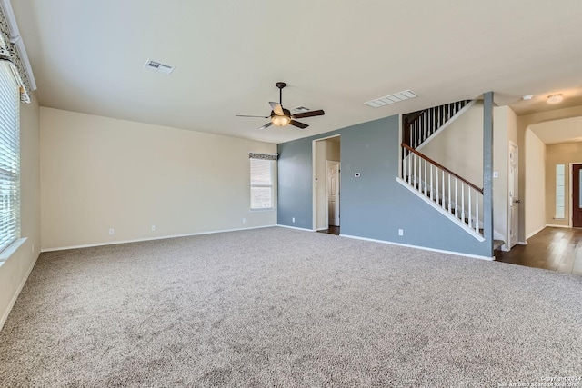 carpeted spare room featuring stairway, ceiling fan, visible vents, and baseboards