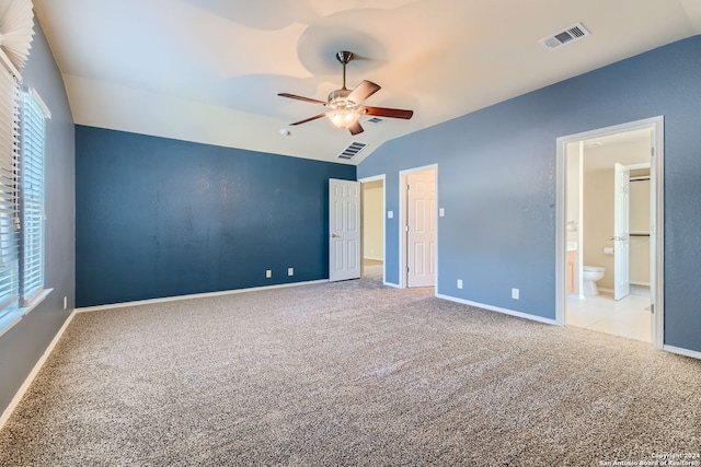 unfurnished bedroom with lofted ceiling, ceiling fan, ensuite bathroom, and light carpet