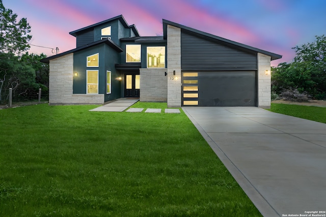 contemporary home featuring driveway, a garage, stone siding, a front lawn, and stucco siding