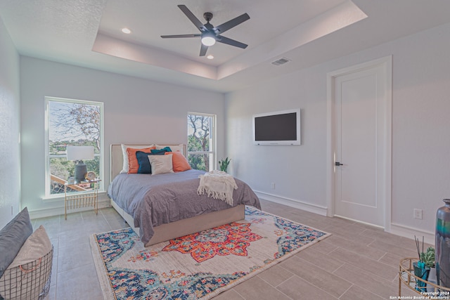 bedroom featuring a tray ceiling, recessed lighting, visible vents, ceiling fan, and baseboards