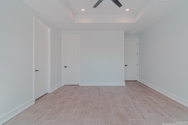 unfurnished bedroom with a raised ceiling and ceiling fan