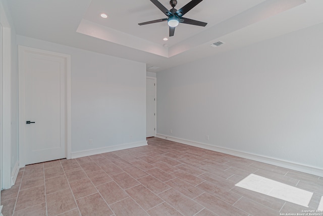 unfurnished room with a raised ceiling and ceiling fan