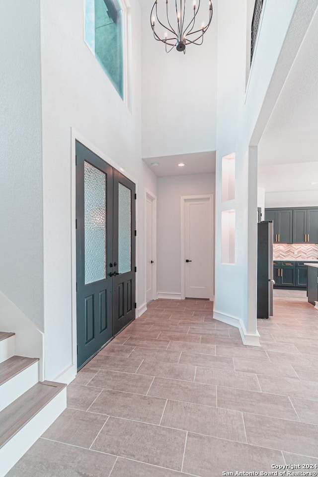 entrance foyer with baseboards, visible vents, stairway, french doors, and a notable chandelier