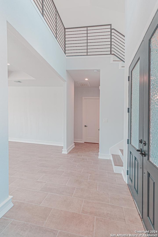 entrance foyer featuring french doors, stairway, a high ceiling, and baseboards