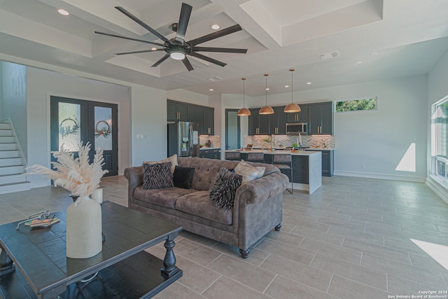 living area featuring baseboards, coffered ceiling, a wealth of natural light, and french doors