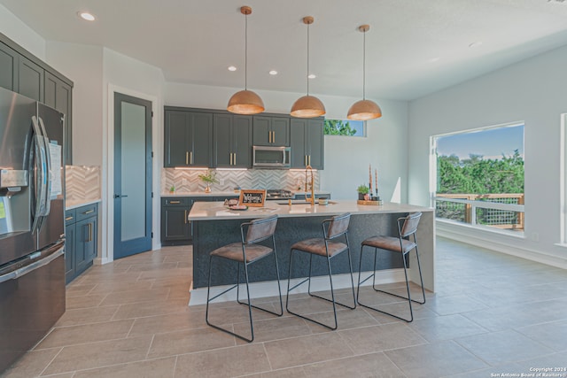 kitchen with pendant lighting, a breakfast bar area, stainless steel appliances, tasteful backsplash, and light countertops