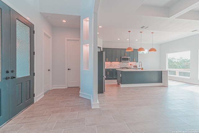 kitchen featuring backsplash, decorative light fixtures, stainless steel appliances, sink, and a kitchen island with sink