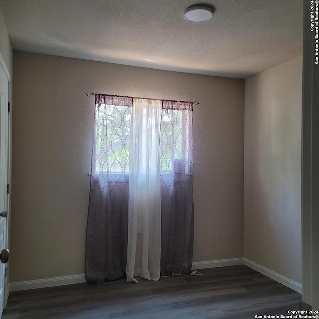 empty room with a textured ceiling and dark hardwood / wood-style flooring