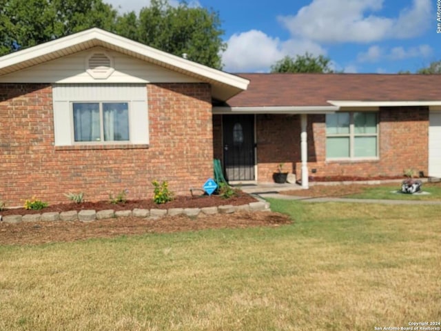 view of front of home with an attached garage, brick siding, and a front yard