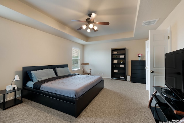 bedroom featuring light colored carpet, ceiling fan, and a tray ceiling