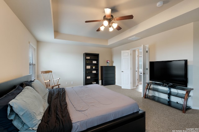 carpeted bedroom with a tray ceiling and ceiling fan