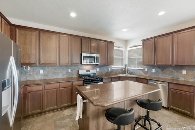 kitchen featuring a kitchen island, a breakfast bar area, appliances with stainless steel finishes, sink, and decorative backsplash