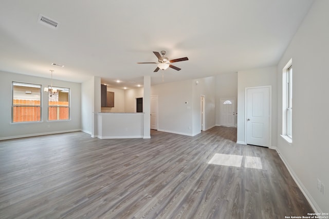 unfurnished living room featuring ceiling fan with notable chandelier and hardwood / wood-style flooring