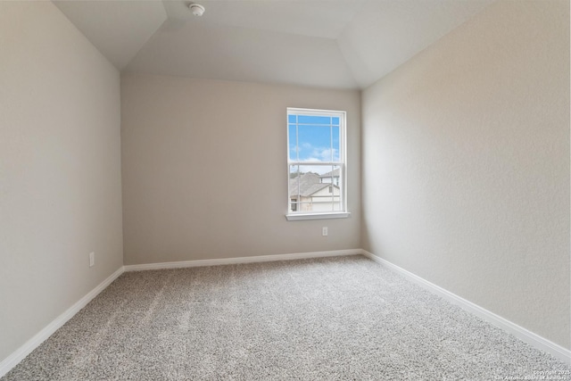 empty room featuring lofted ceiling, carpet, and baseboards