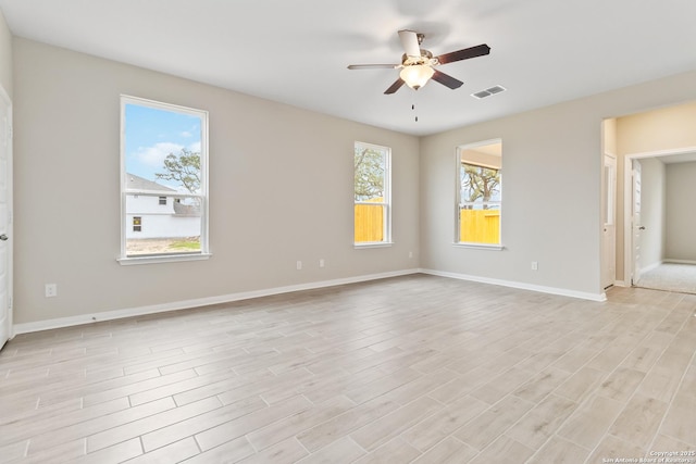 spare room with ceiling fan, baseboards, visible vents, and light wood-style floors