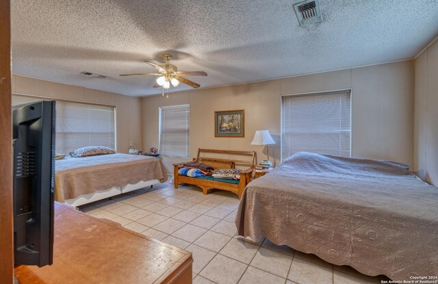 bedroom with a textured ceiling, ceiling fan, and light tile patterned floors