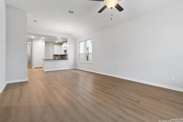 unfurnished living room featuring ceiling fan with notable chandelier, light wood-type flooring, and sink