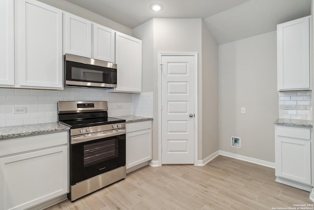 kitchen with white cabinets, light stone countertops, light wood-style flooring, and stainless steel appliances