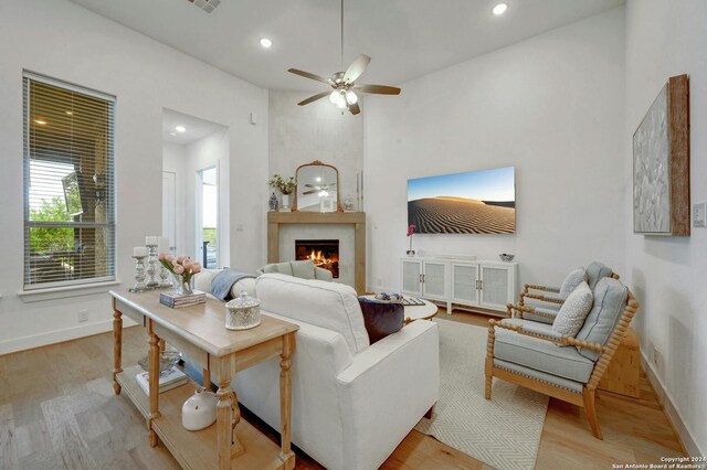 living room featuring a large fireplace, ceiling fan, and light hardwood / wood-style floors