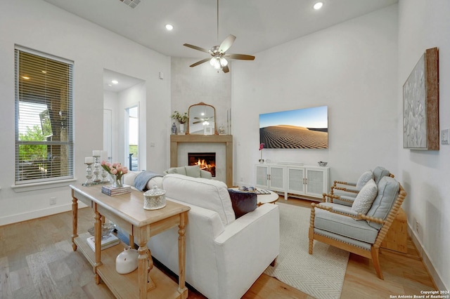 living room featuring a fireplace, light wood-style flooring, and baseboards