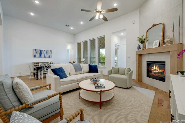 living room with ceiling fan, light wood-type flooring, and a fireplace