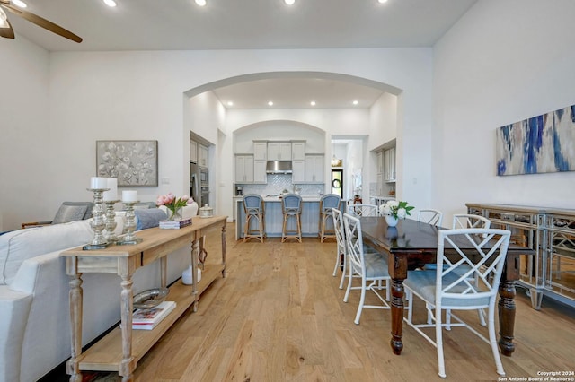 dining area with arched walkways, ceiling fan, recessed lighting, and light wood-style floors