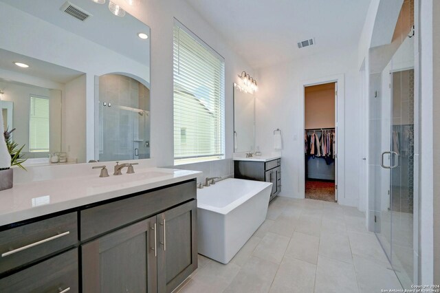 bathroom with tile patterned flooring, vanity, and plus walk in shower