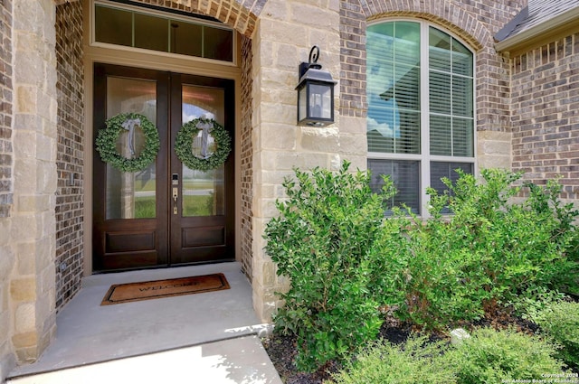 view of exterior entry featuring french doors and brick siding