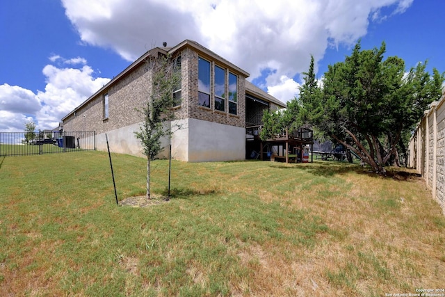 view of side of property with brick siding, fence, and a lawn