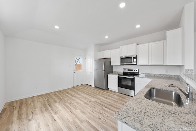 kitchen featuring light stone countertops, appliances with stainless steel finishes, sink, white cabinetry, and light wood-type flooring