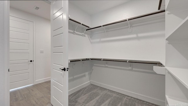 walk in closet with light hardwood / wood-style floors